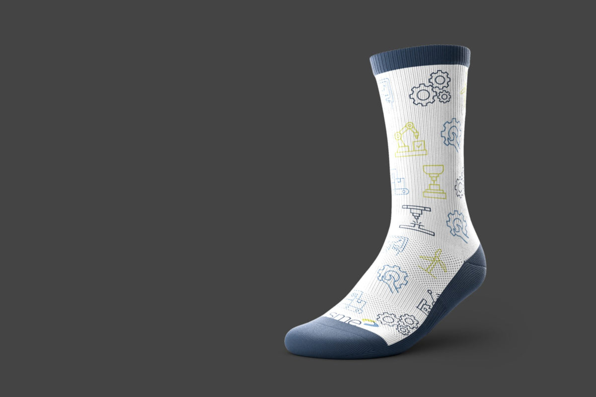 A single performance crew sock shown on a dark gray background. The sock is white with a pattern of small blue and light green technical icons, and has solid navy blue cuffs, heel, and toe. Features SME logo near the toe.