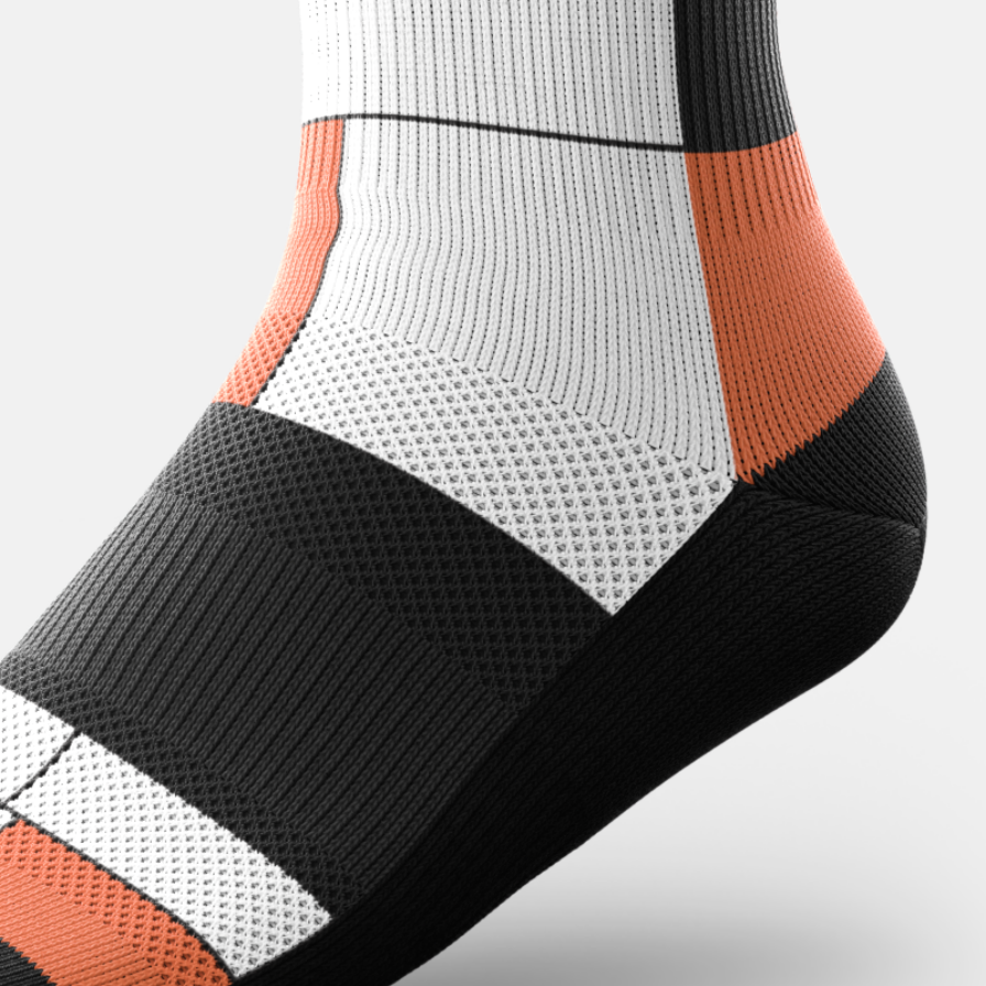 Close-up of a ribbed preformance sock with a color-blocked pattern of black, white, and orange, showing textured knit details on a light gray background.