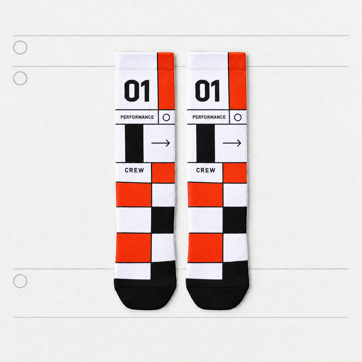 A pair of crew socks with a bold geometric pattern of white, black, and orange blocks, featuring the text '01', 'PERFORMANCE', 'CREW', and an arrow. Flat on a light gray background with horizontal lines.